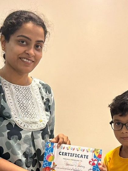 A young boy proudly accepts his summer camp certificate, a symbol of his creative achievements and the fun he had with us.