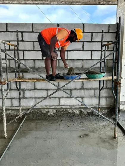 A mason at work, carefully laying concrete blocks. Craftsmanship matters to me, and I ensure my team is focused on quality in every single detail.