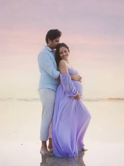 A tender embrace by the sea. This couple's portrait against the soft pastel colors of a sunset sky is the epitome of romance and shared dreams.