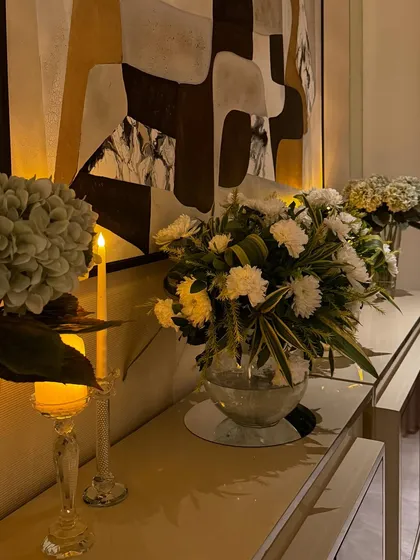 A beautiful floral arrangement in a glass vase, illuminated by candlelight. We placed this on a console table to add a touch of elegance and warmth to the living space for an intimate home gathering.