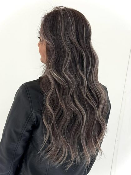 A perfect ash balayage for long, wavy hair. The cool, silvery highlights are expertly blended with the darker base for a dramatic yet sophisticated look.