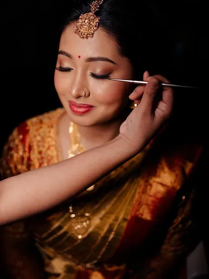 A quiet moment during the getting-ready process. This candid shot captures the delicate application of eyeliner, a crucial step in defining the eyes for a classic bridal look that will last through the entire ceremony.