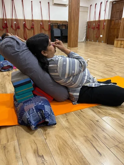 A close-up of a student practicing alternate nostril breathing while supported by props. This pranayama technique is known for balancing the nervous system and calming the mind.