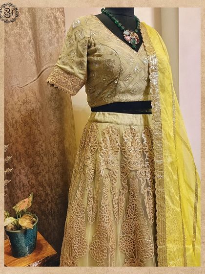 A closer view of the green embroidered lehenga, showing the texture of the net fabric and the craftsmanship of the golden threadwork.