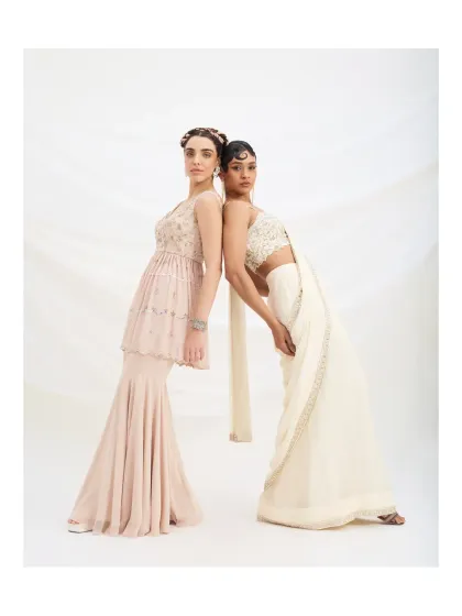 A creative pose showcasing the beautiful silhouettes of the pastel sharara set and the ivory pre-draped saree. These are perfect choices for bridesmaids or wedding guests.