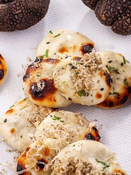 Miniature naans are topped with freshly shaved black truffle, an indulgent and aromatic bread that perfectly complements our tasting menus.