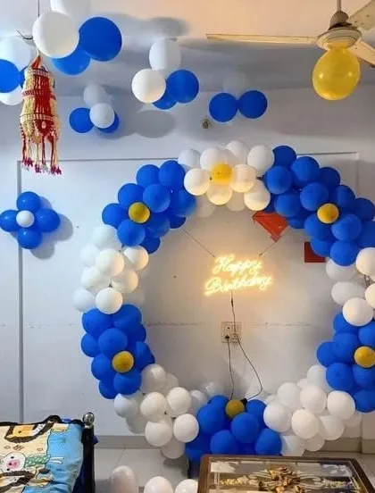 A blue and white balloon ring decorated with flower-like clusters and a neon sign.
