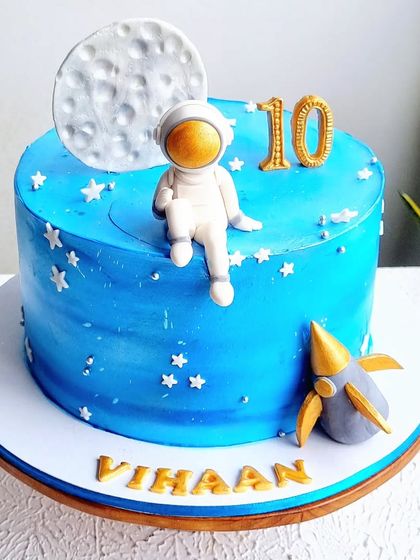 A closer view of the space-themed cake, focusing on the astronaut and moon topper.