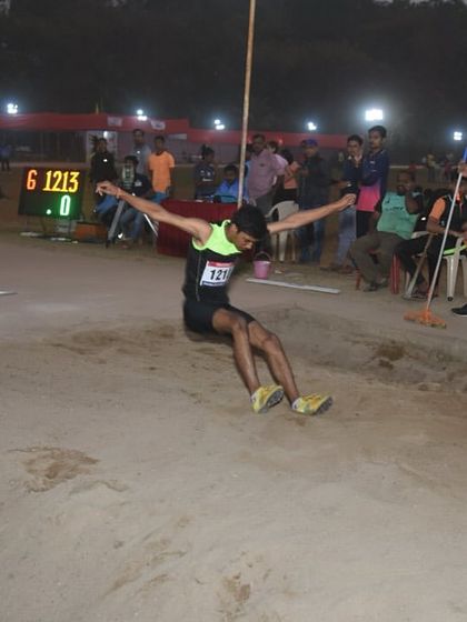 A long jumper in mid-air, captured during our night event. The electronic display in the background shows the precision we bring to every jump.