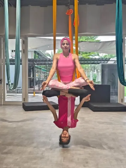 Aerial yoga is an art form. Here, a mother and daughter create a stunning lotus reflection pose, a beautiful example of the serene and creative partner work we explore in our classes.