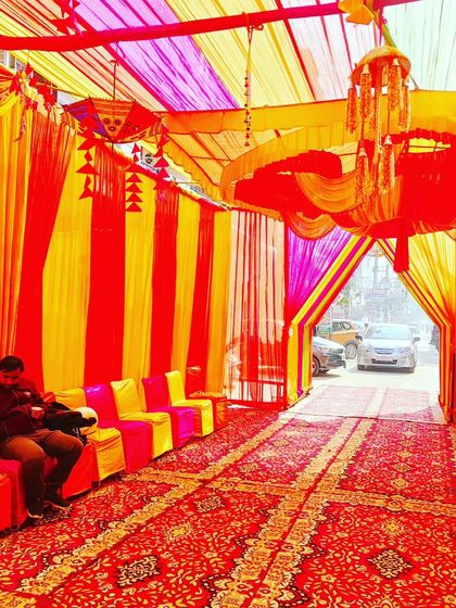 The entrance to the red and yellow themed tent, with a beautifully decorated chandelier and comfortable seating for arriving guests.