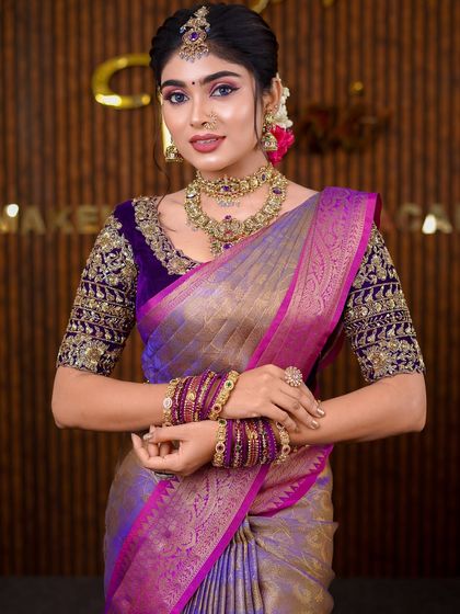 A stunning purple and gold Kanchipuram saree. The draping style is grand and traditional, perfect for a classic bridal photoshoot.