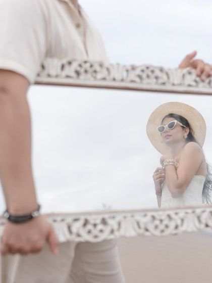 A creative shot using a mirror to frame the bride's reflection. This is a unique and artistic way to capture a portrait during a beach shoot.