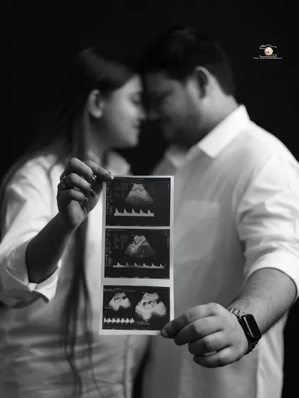 A powerful black and white portrait of an expecting couple holding up their ultrasound photos. This classic, minimalist shot focuses on the miracle they are waiting for.