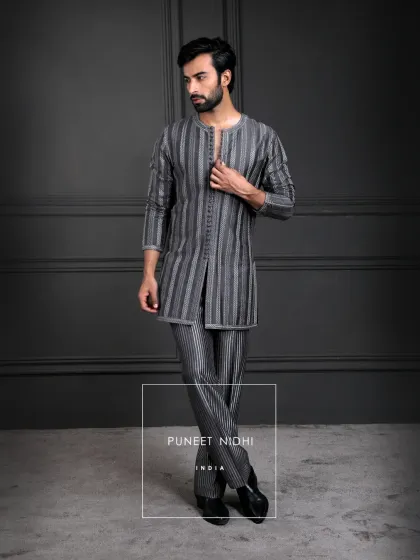 Charcoal grey geometry in motion. This kurta set features linear patterns, a lustrous texture, and a sharp straight cut, with heritage detailing in the looped buttons.
