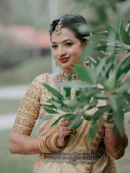 A candid shot of the bride, her makeup looking fresh and natural against the lush green background.