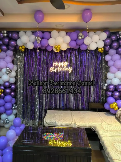 A purple, white, and silver balloon arch with a neon sign, creating a stylish and modern birthday party vibe at home.