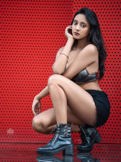 A dynamic crouching pose against the red wall, with the reflection on the floor adding another visual element. This shot is full of energy and modern style.