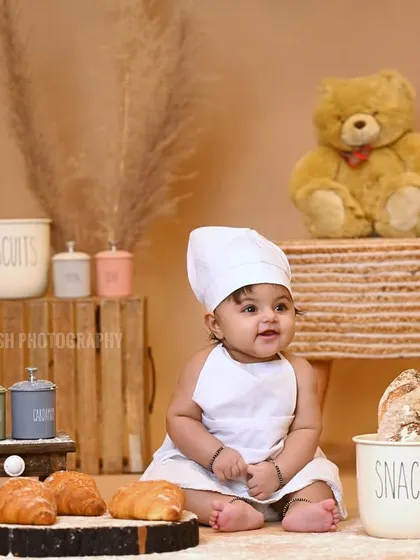The little chef sitting amongst his props, including croissants and snack jars.