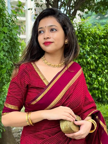 A candid-style shot looking away, highlighting the temple jewellery necklace and the texture of the saree fabric.