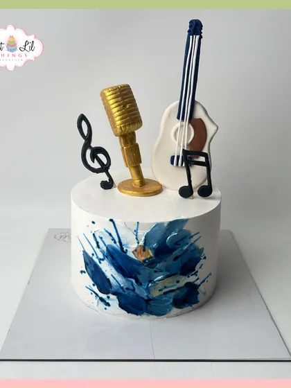 A cake for the music lover, featuring a golden microphone, a guitar, and musical notes against an abstract blue background.