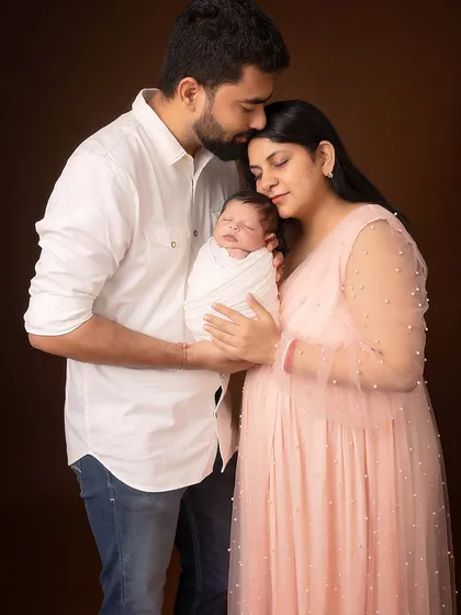 A color portrait of the new family of three. The parents' serene expressions and the sleeping baby create a peaceful and loving tableau.