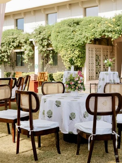 A serene corner of the Mehendi venue, with beautifully set tables overlooking the lush greenery and heritage architecture.