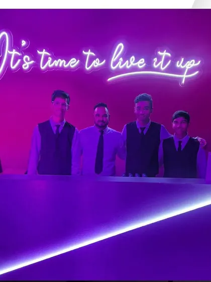 Our team at the HSBC event, standing before a neon sign that reads "It's time to live it up."