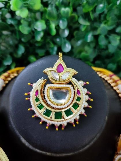 A beautiful maang tikka with a unique lotus motif and colorful stones.