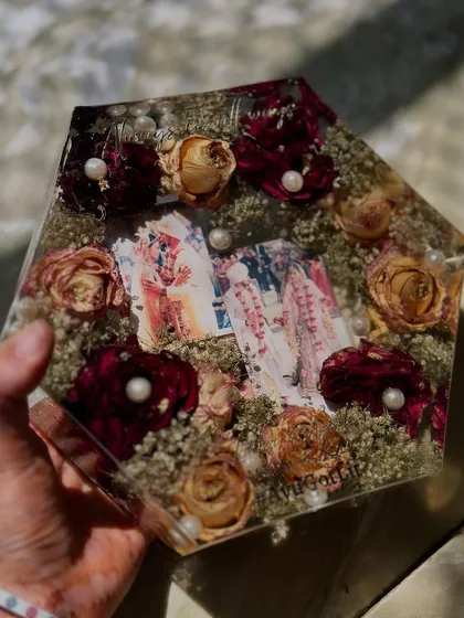 This hexagonal keepsake is filled with a mix of red and white roses, creating a rich texture around the couple's photos.