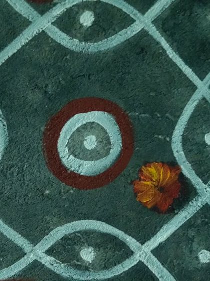 A close-up detail of the kolam mural. You can see the texture of the wall and the hand-painted quality of the lines and dots, which gives the piece an authentic, rustic feel inspired by traditional South Indian floor art.