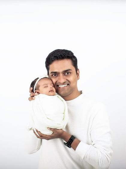 A proud father cradles his newborn daughter. The minimalist white background ensures that this powerful, loving moment is the only focus.