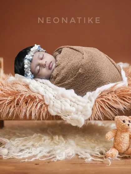 Tucked in and cozy. A sleeping newborn on a tiny wooden bed, surrounded by teddy bears. This is a classic and heartwarming setup.