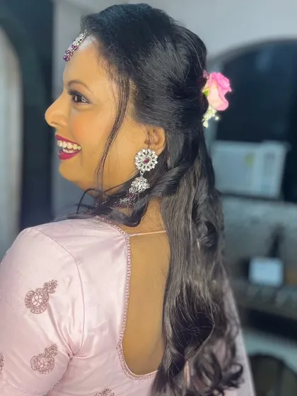 A side view of her hairstyle, which is a simple half-updo with curls, decorated with a small flower.