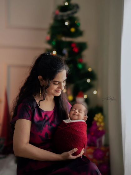 A smiling newborn wrapped snugly for a Christmas-themed photoshoot. I ensure babies are safe and comfortable while capturing these adorable expressions.