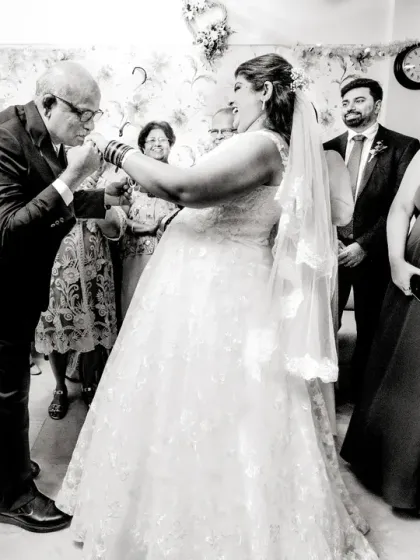 A touching gesture as a father kisses his daughter's hand, a sign of his blessing and love. This black and white photo captures the emotion of the moment beautifully.