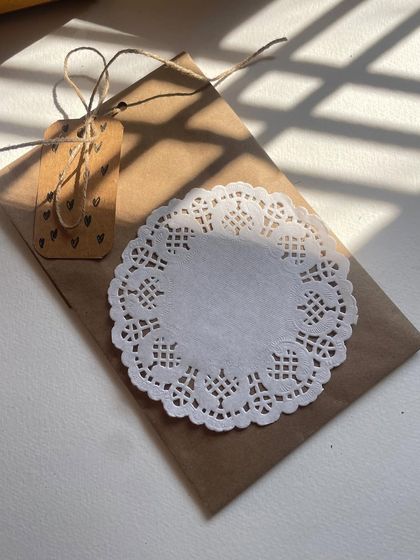 A simple and elegant birthday card, wrapped in a kraft paper envelope with a doily and a hand-stamped tag. Ready for your personal message.