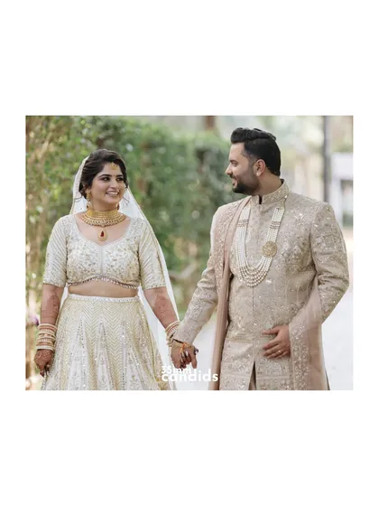 A classic couple portrait, holding hands and sharing a look of love. Their coordinated outfits and happy smiles make for a perfect, timeless wedding photo.