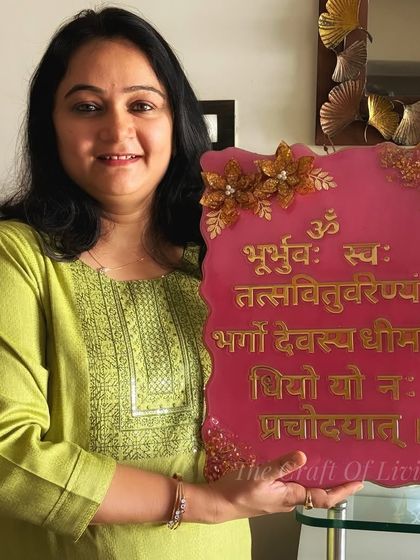 Here I am, holding a custom-made Gayatri Mantra plaque. It was a joy to create this piece, which blends sacred verses with floral artistry, for a client's home.
