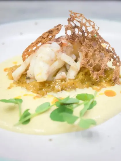 For a taste of luxury, I present my confit lobster tail. It's served on a bed of saffron leeks fondue with a corn and lemongrass velouté, finished with a touch of chili oil.