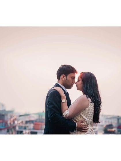 A silhouette-style portrait against the evening sky and the backdrop of boats in the harbour, capturing a moody and cinematic pre-wedding scene.