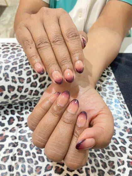 A darker, more dramatic take on the ombre trend. This design uses a deep burgundy color that fades from the tips into a natural nude base on rounded nails, creating a chic and moody effect.