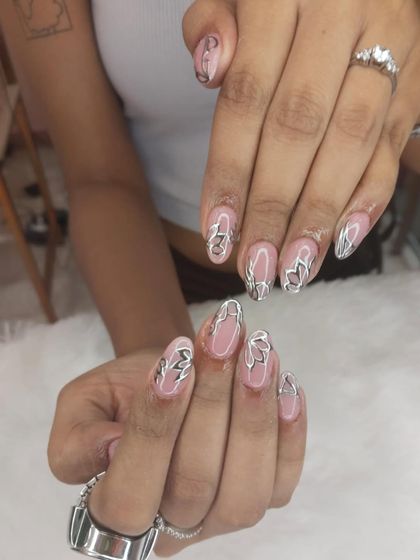 A trendy and modern design using 3D silver chrome. The abstract, fluid shapes are applied over a sheer pink base for a chic and edgy look.