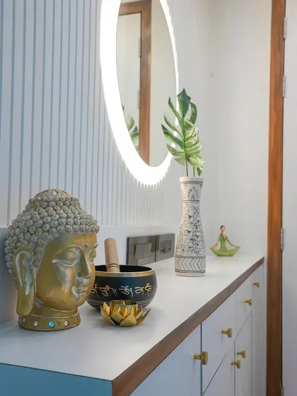 Peace and tranquility greet you at this entryway, featuring a serene Buddha statue, a singing bowl, and a backlit mirror against a fluted wall panel.