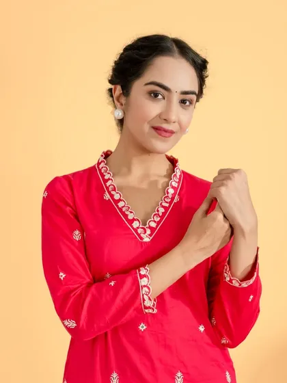 A close-up portrait of a model in a vibrant red kurta with detailed embroidery around the neckline. This shot effectively showcases the craftsmanship of the garment.