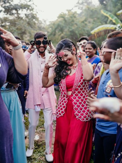 The couple dancing with friends, wearing fun party glasses at their Haldi celebration.