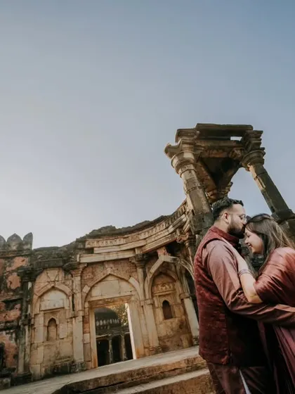 A low-angle, wide shot that emphasizes the scale of the ancient ruins. The couple shares a tender moment, creating a beautiful contrast between enduring love and timeless architecture.