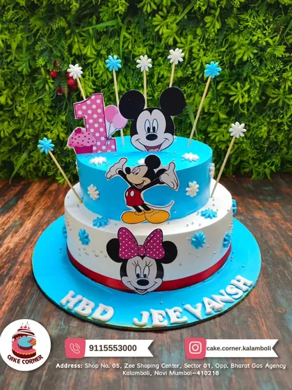 A classic two-tier Mickey and Minnie Mouse cake for a first birthday. The bright blue and white design with character toppers is a timeless choice for a little one's celebration.