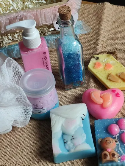 A close-up of some of the items in a baby shower gift basket, including baby-themed soaps, body wash, and bath salts.