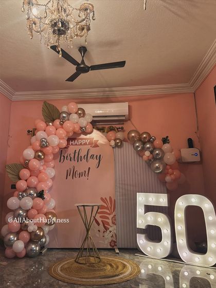 We curated this elegant 50th birthday decor for a client's mom. The setup features a soft pink backdrop, a beautiful balloon arch in rose gold and silver, and large marquee numbers.